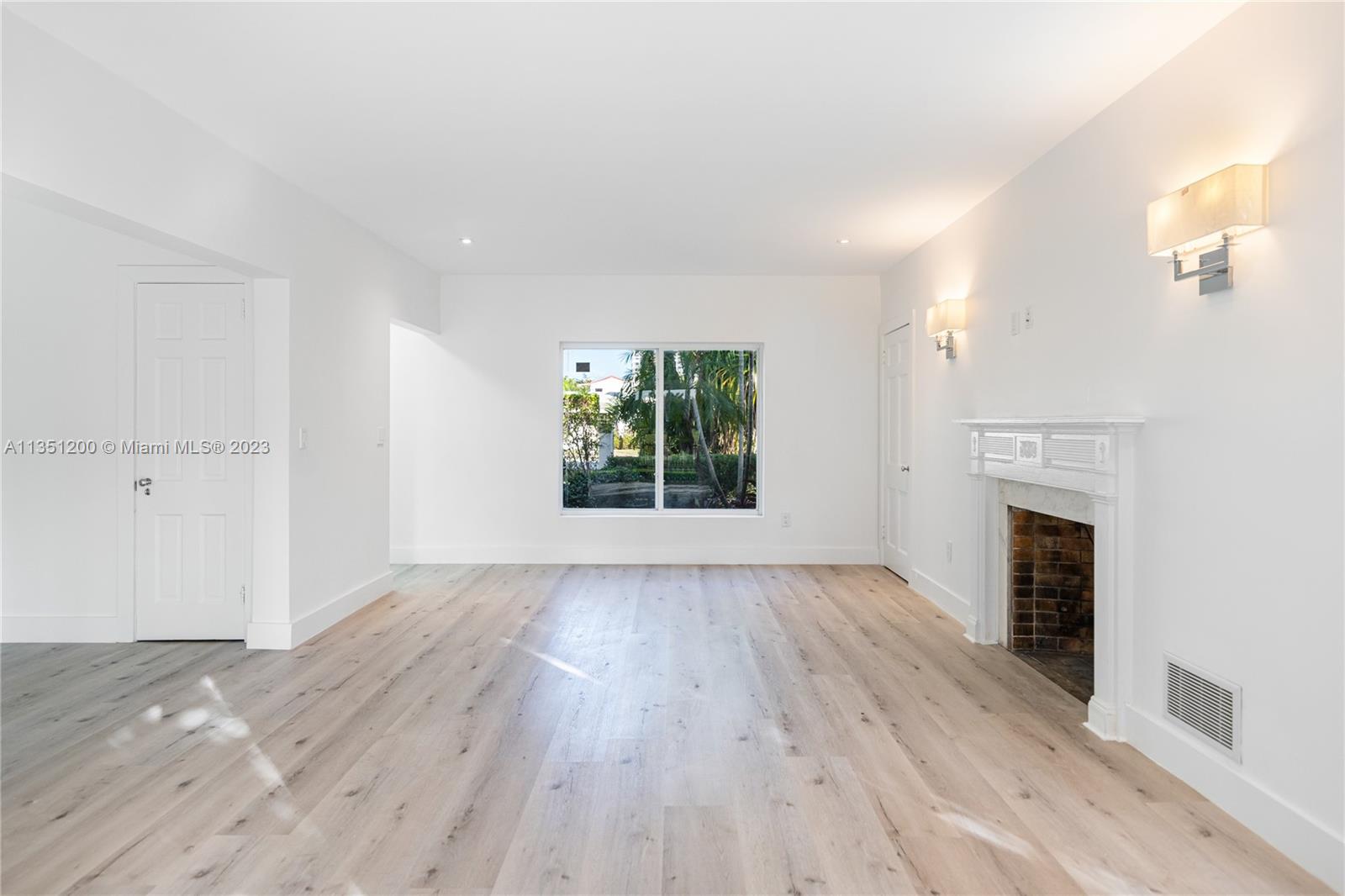 5512 La Gorce Drive Miami Beach, FL 33140 - Photo 9 of 35 an empty room with wooden floor a fireplace and windows