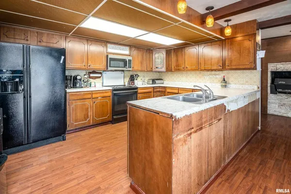 a kitchen with stainless steel appliances granite countertop wooden cabinets a sink and dishwasher a stove with wooden floor