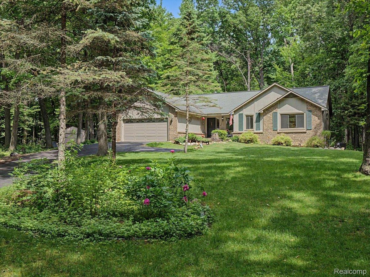 9714 Naiad Road Clarkston, MI 48348 - Photo 58 of 61 A charming ranch-style residence showcasing a brick façade with shuttered windows, a two-car garage, and thoughtfully maintained landscaping set against a backdrop of mature woods.
