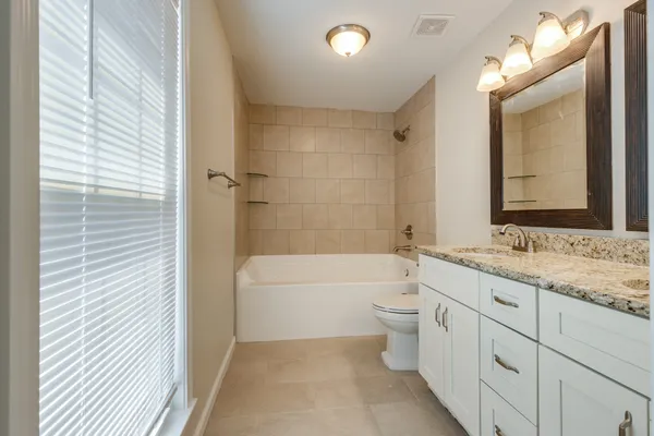 a bathroom with a double vanity sink toilet and bathtub