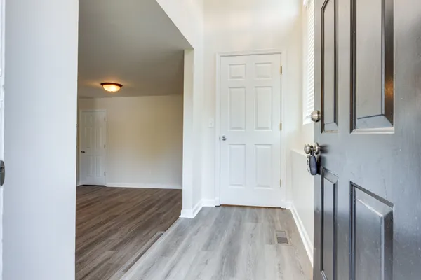 an empty room with wooden floor fireplace and windows