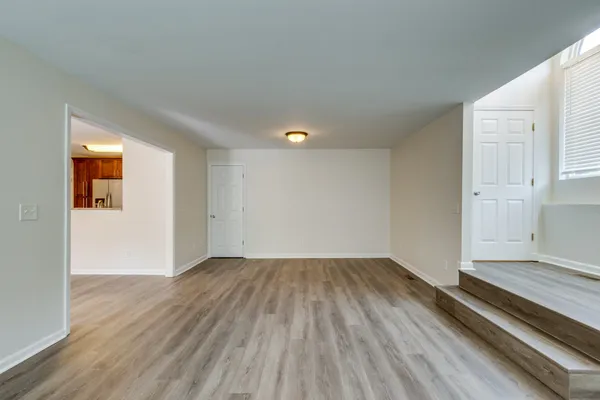 an empty room with wooden floor fireplace and windows