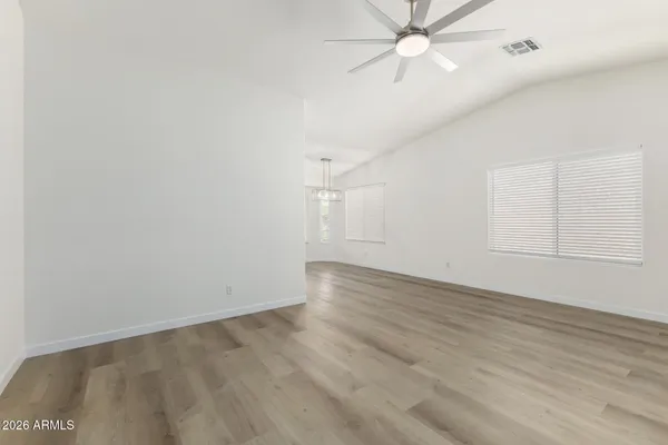 an empty room with wooden floor fan and windows