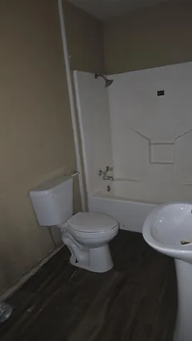 a white toilet sitting next to a bath tub