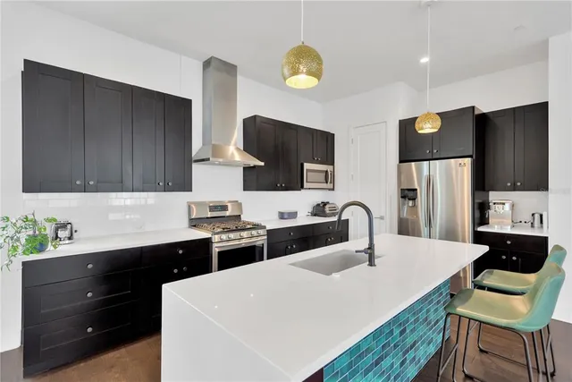 a kitchen with stainless steel appliances a sink dishwasher a refrigerator a stove and a microwave with wooden floor