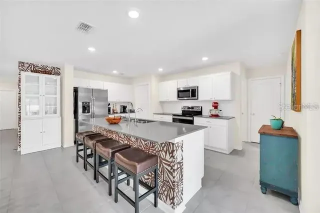 a kitchen with stainless steel appliances kitchen island granite countertop a refrigerator and a stove top oven