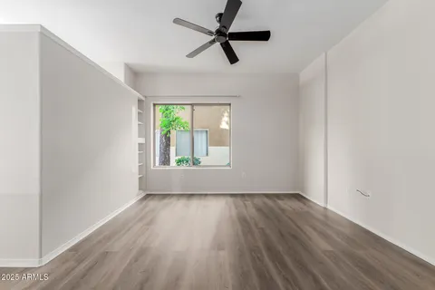 an empty room with wooden floor fan and windows