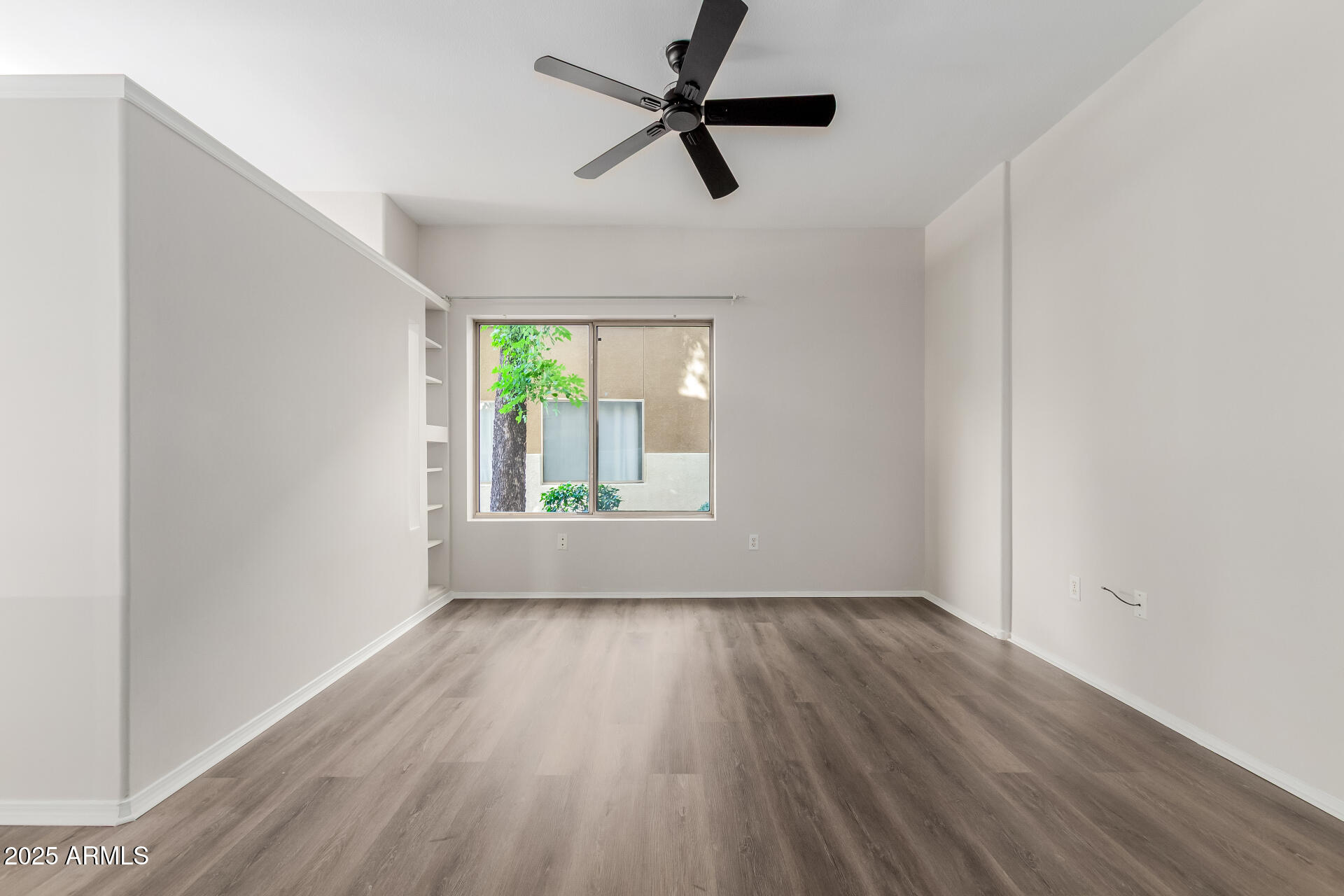 4644 North 22nd Street, Unit 1161 Phoenix, AZ 85016 - Photo 5 of 25 an empty room with wooden floor fan and windows