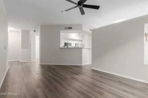 an empty room with wooden floor fan and windows