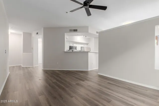 an empty room with wooden floor fan and windows