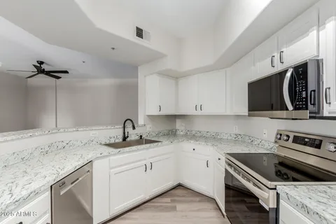 a kitchen with granite countertop a sink stainless steel appliances and white cabinets