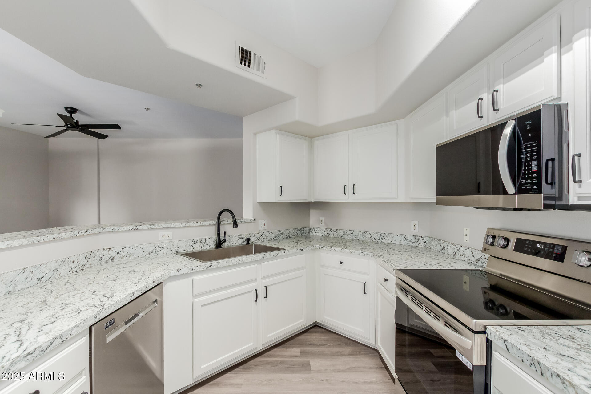 4644 North 22nd Street, Unit 1161 Phoenix, AZ 85016 - Photo 9 of 25 a kitchen with granite countertop a sink stainless steel appliances and white cabinets