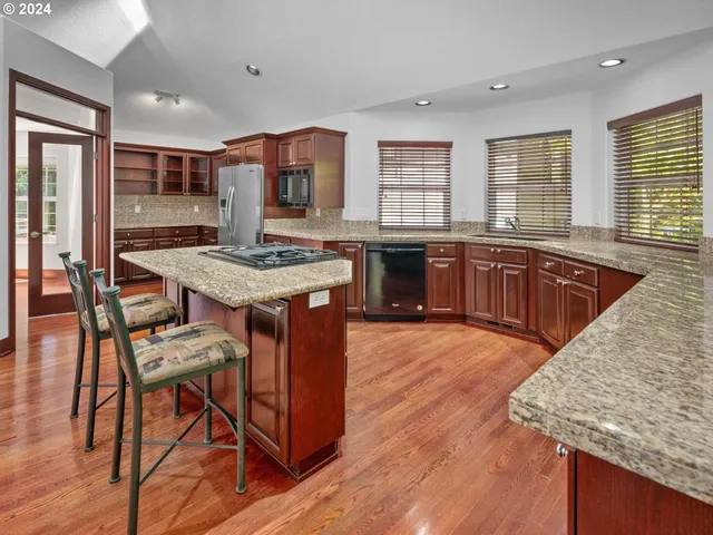 a kitchen with kitchen island granite countertop a stove and a sink