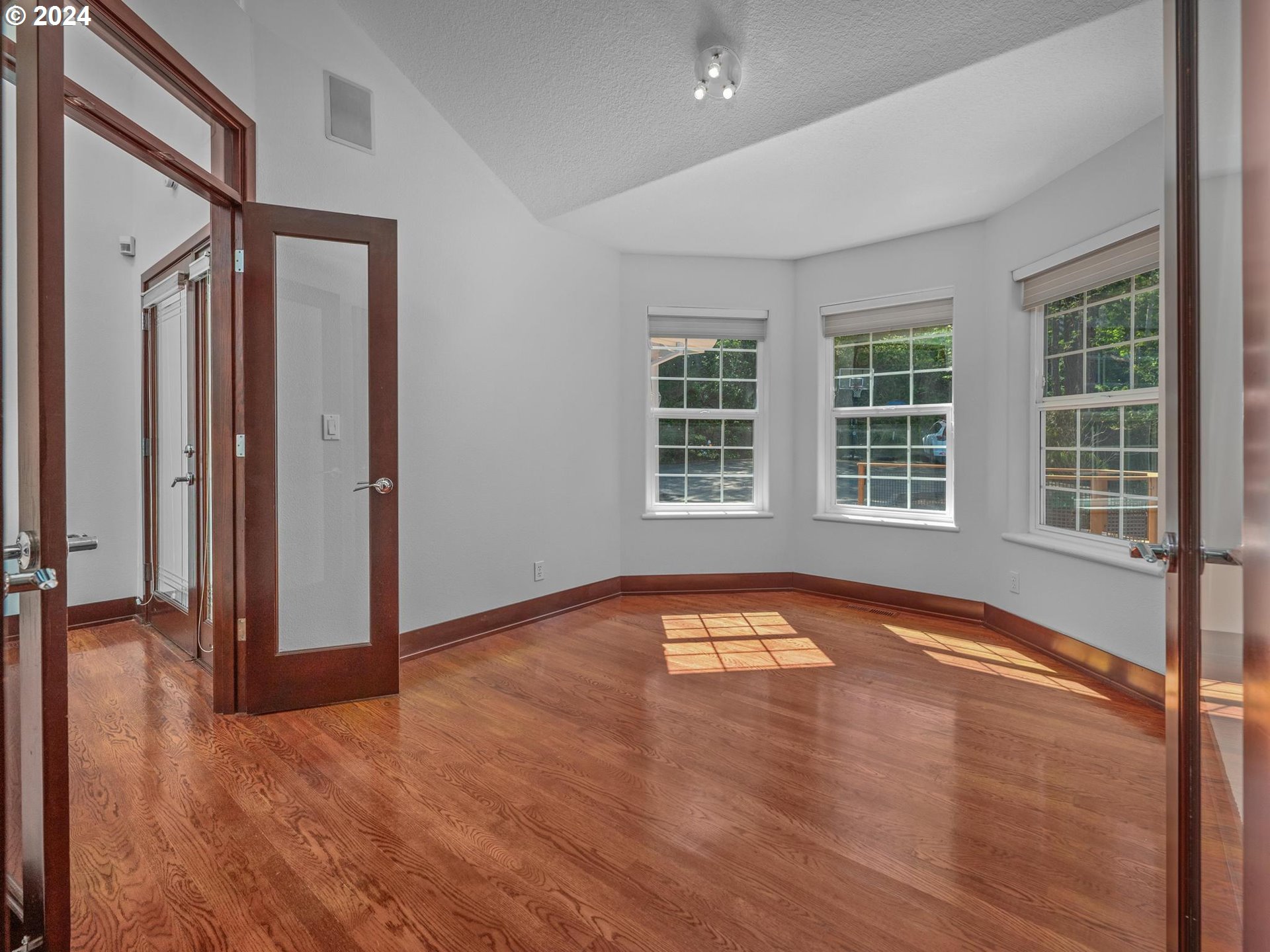 6254 Southwest Burlingame Avenue, Unit A Portland, OR 97239 - Photo 15 of 44 an empty room with wooden floor and windows