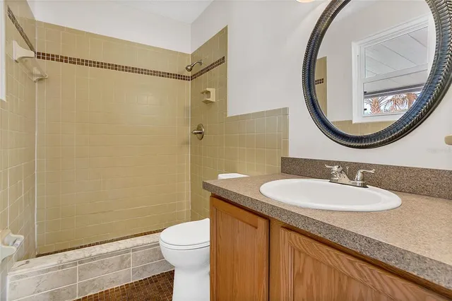 a bathroom with a granite countertop sink mirror vanity and toilet