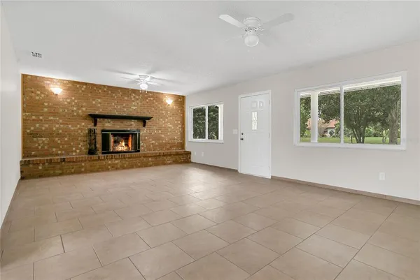 an empty room with windows and fireplace