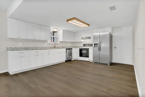 a kitchen with stainless steel appliances granite countertop a sink and a refrigerator