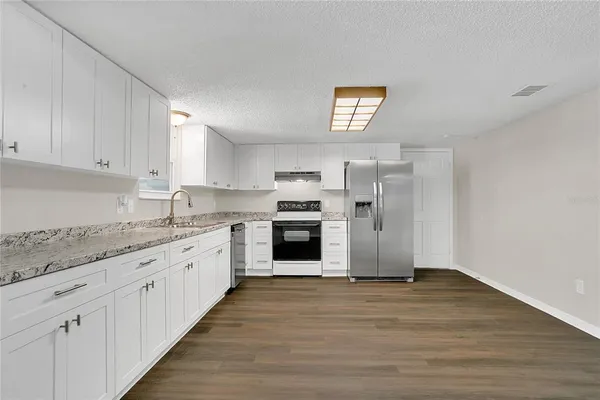 a kitchen with granite countertop a stove top oven and cabinets