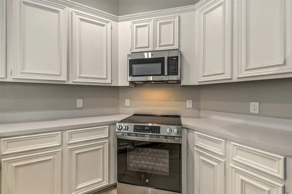 a kitchen with stainless steel appliances granite countertop white cabinets and a stove top oven