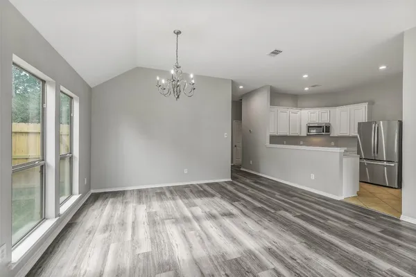 a view of kitchen and empty room with wooden floor