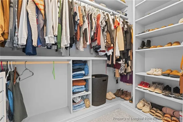 a view of walk in closet with clothes and shoes