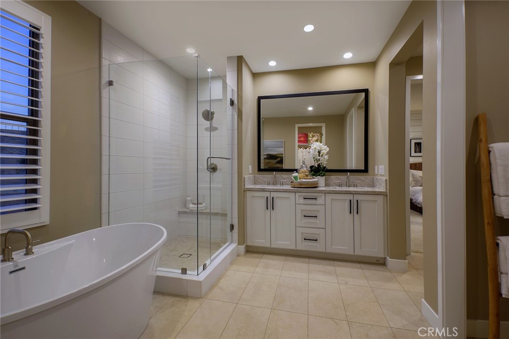 218 Maricopa Irvine, CA 92618 - Photo 5 of 10 a bathroom with a granite countertop sink a mirror a bathtub and shower