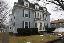 a view of a brick house with a yard plants and large tree