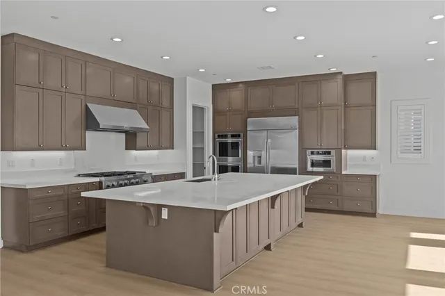 a large kitchen with stainless steel appliances a sink stove and cabinets