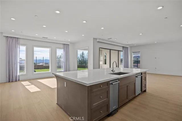 a large white kitchen with kitchen island a sink stainless steel appliances and cabinets