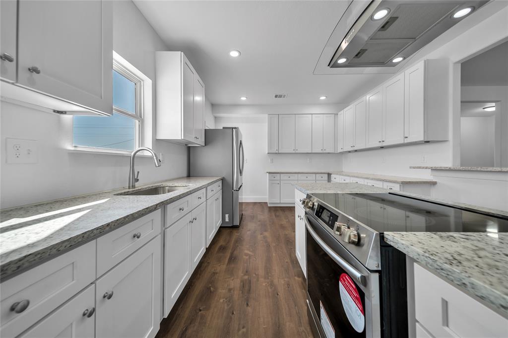 1128 Newton Road Ferris, TX 75125 - Photo 5 of 19 Kitchen featuring appliances with stainless steel finishes, light stone countertops, white cabinets, dark wood-style floors, and extractor fan