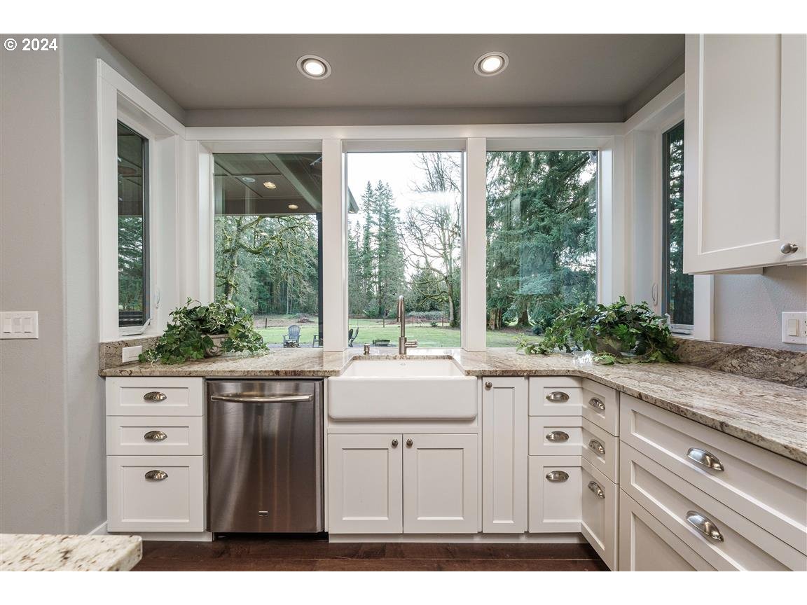 27015 Northeast Hathaway Road Camas, WA 98607 - Photo 12 of 48 a kitchen with granite countertop a stove a sink and white cabinets with wooden floor