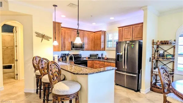a kitchen with stainless steel appliances granite countertop a refrigerator a sink a stove and chairs