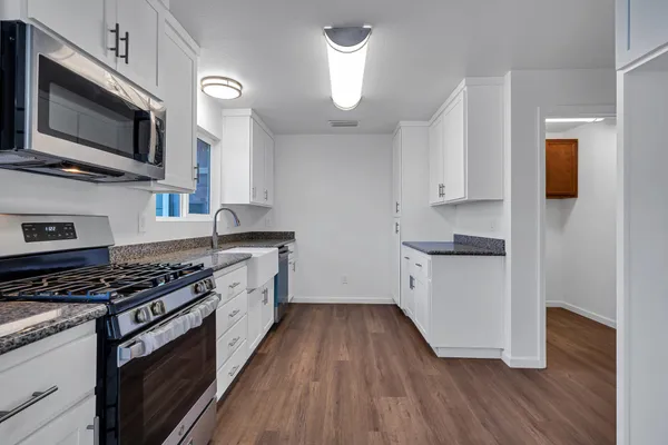 a kitchen with white cabinets and wooden floor