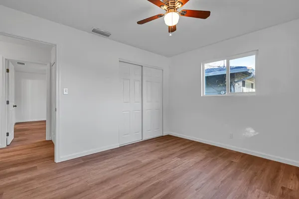 a view of an empty room with wooden floor and a window