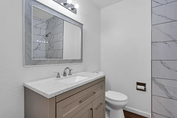 a bathroom with a granite countertop sink toilet and shower