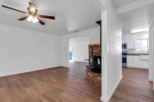 a view of a livingroom with wooden floor a ceiling fan and windows