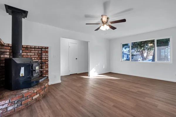 a view of a livingroom with wooden floor a ceiling fan and windows