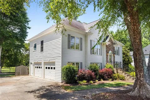 a view of a house with backyard and trees in the background