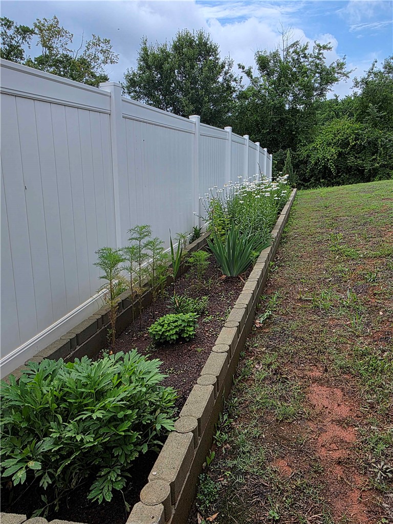 224 Bronson Ridge Anderson, SC 29621 - Photo 36 of 42 A well-maintained garden bed runs alongside a private vinyl fence, creating a secluded outdoor space.