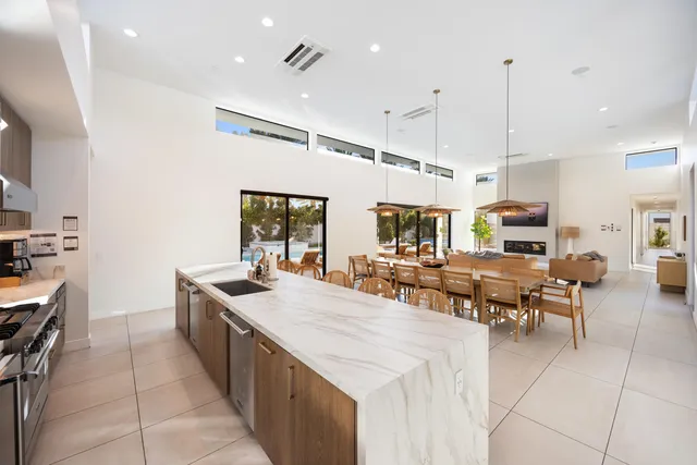 a kitchen with kitchen island a stove a sink a oven a dining table and chairs with wooden floor