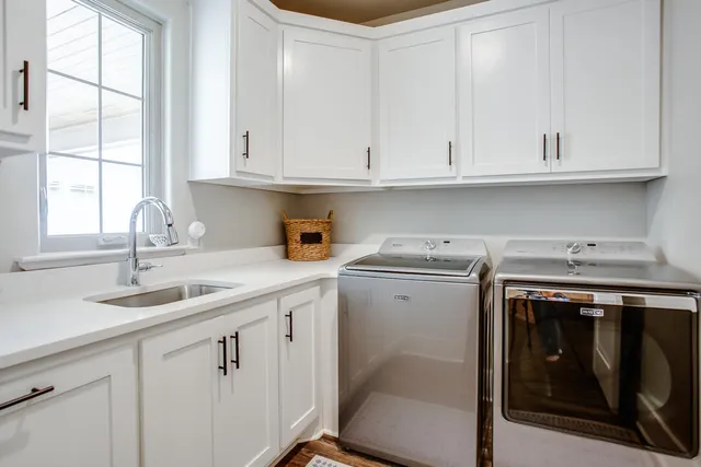 a kitchen with white cabinets and sink