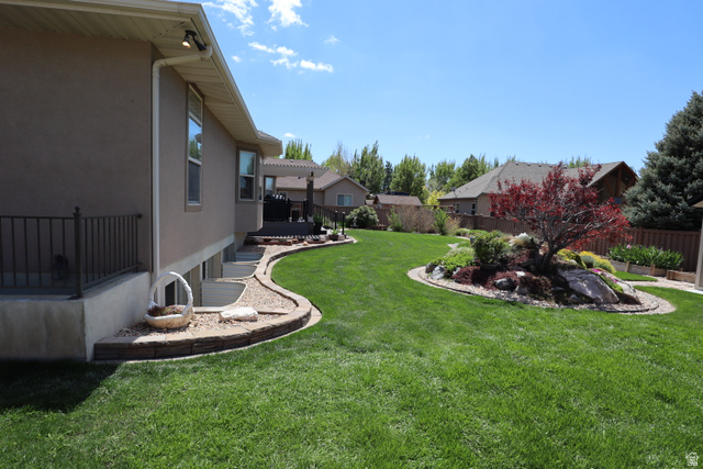 1055 North 1000 East Mapleton, UT 84664 - Photo 100 of 112 Expansive backyard featuring a lush green lawn, a decorative island garden bed with a mature red-leafed tree, and natural rock accents