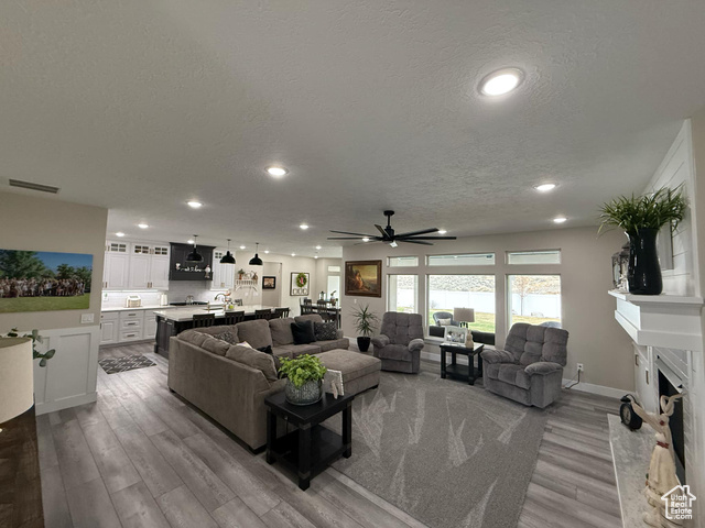 1240 West 2360 North Helper, UT 84526 - Photo 9 of 79 Living room with a premium fireplace, a textured ceiling, visible vents, a ceiling fan, and wood finished floors