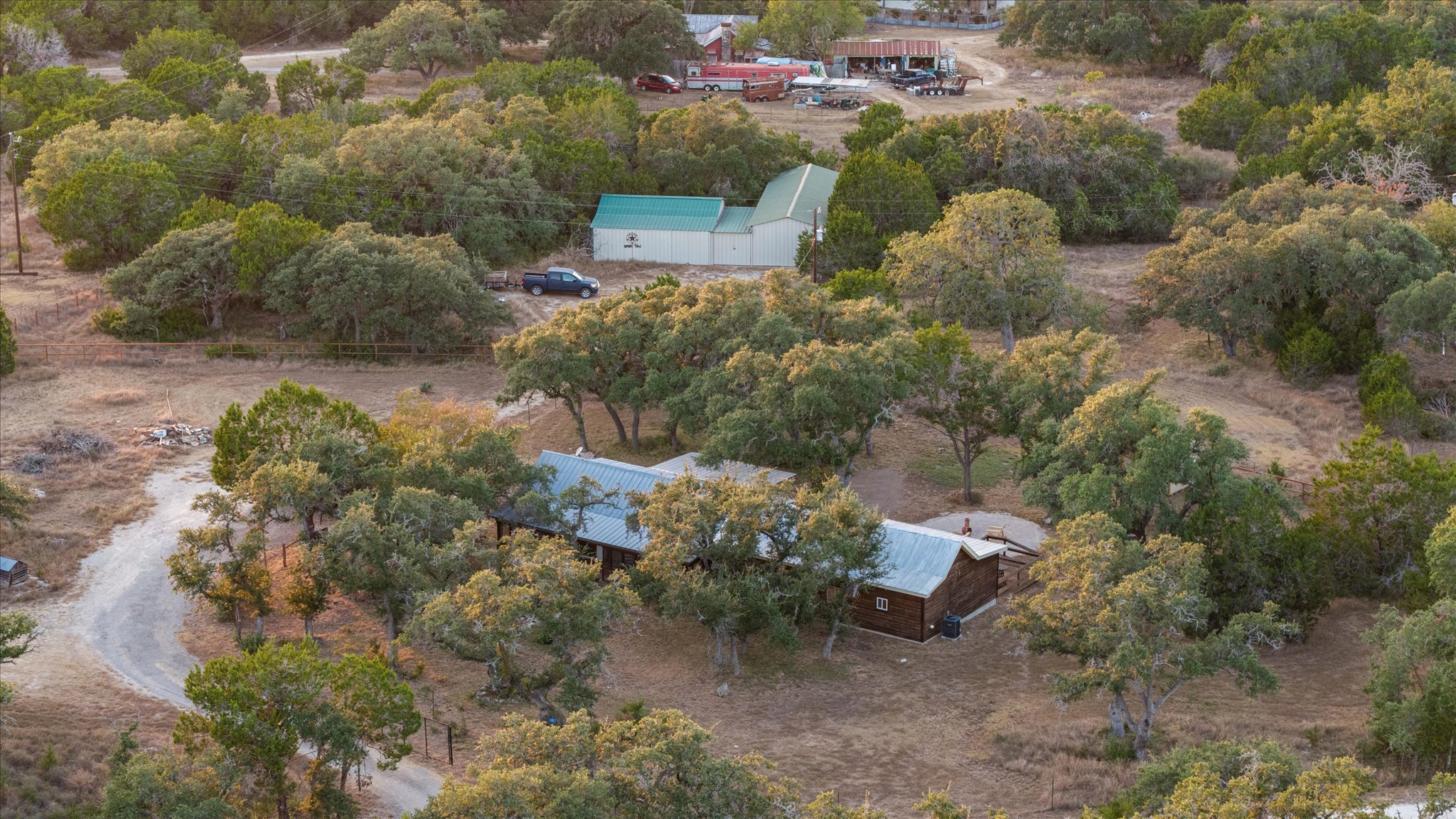 215 Go Away Road Blanco, TX 78606 - Photo 29 of 30 View of the home and 1,520 sq ft barn surrounded by oaks — a perfect balance of privacy and functionality.