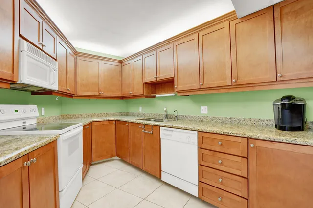 a kitchen with granite countertop a sink and dishwasher a stove with wooden cabinets