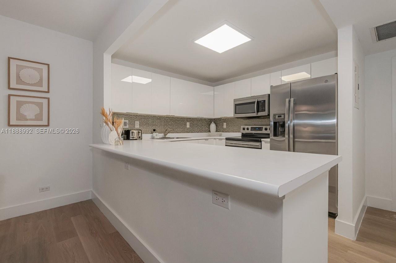 2301 Collins Avenue, Unit 333 Miami Beach, FL 33139 - Photo 12 of 37 a kitchen with kitchen island a sink and refrigerator