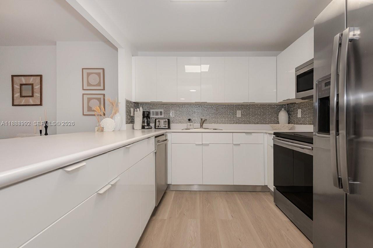 2301 Collins Avenue, Unit 333 Miami Beach, FL 33139 - Photo 16 of 37 a kitchen with a sink white cabinets and stainless steel appliances