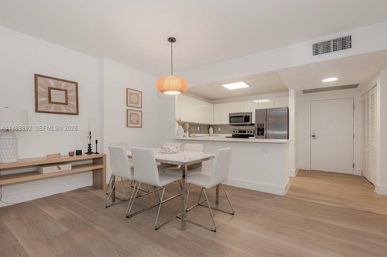 2301 Collins Avenue, Unit 333 Miami Beach, FL 33139 - Photo 8 of 37 a kitchen with kitchen island a dining table chairs and white cabinets