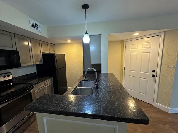 a kitchen with kitchen island a counter space a sink and stainless steel appliances