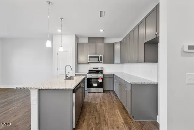 a kitchen with kitchen island granite countertop a sink a counter top space stainless steel appliances and cabinets